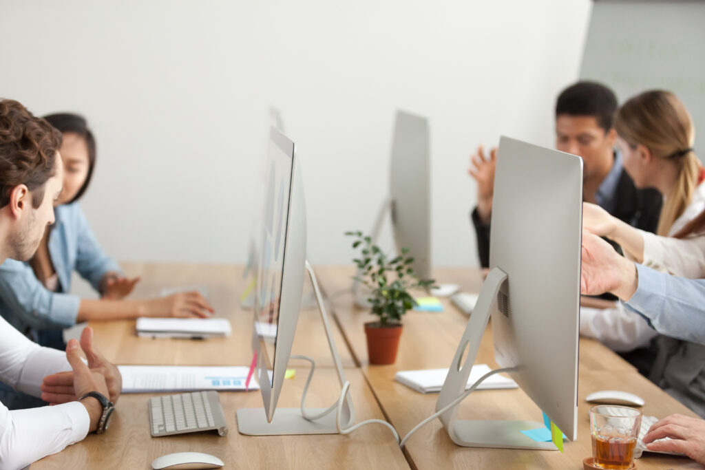 espaço para equipes composto por computadores e com funcionários trabalhando