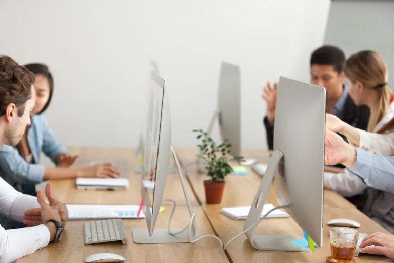 espaço para equipes composto por computadores e com funcionários trabalhando